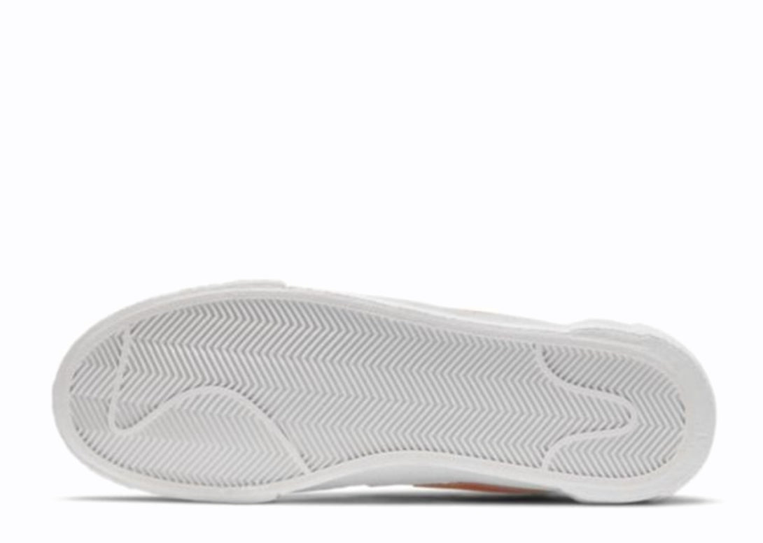 White and orange Nike Blazer Low sneakers displayed on a white background